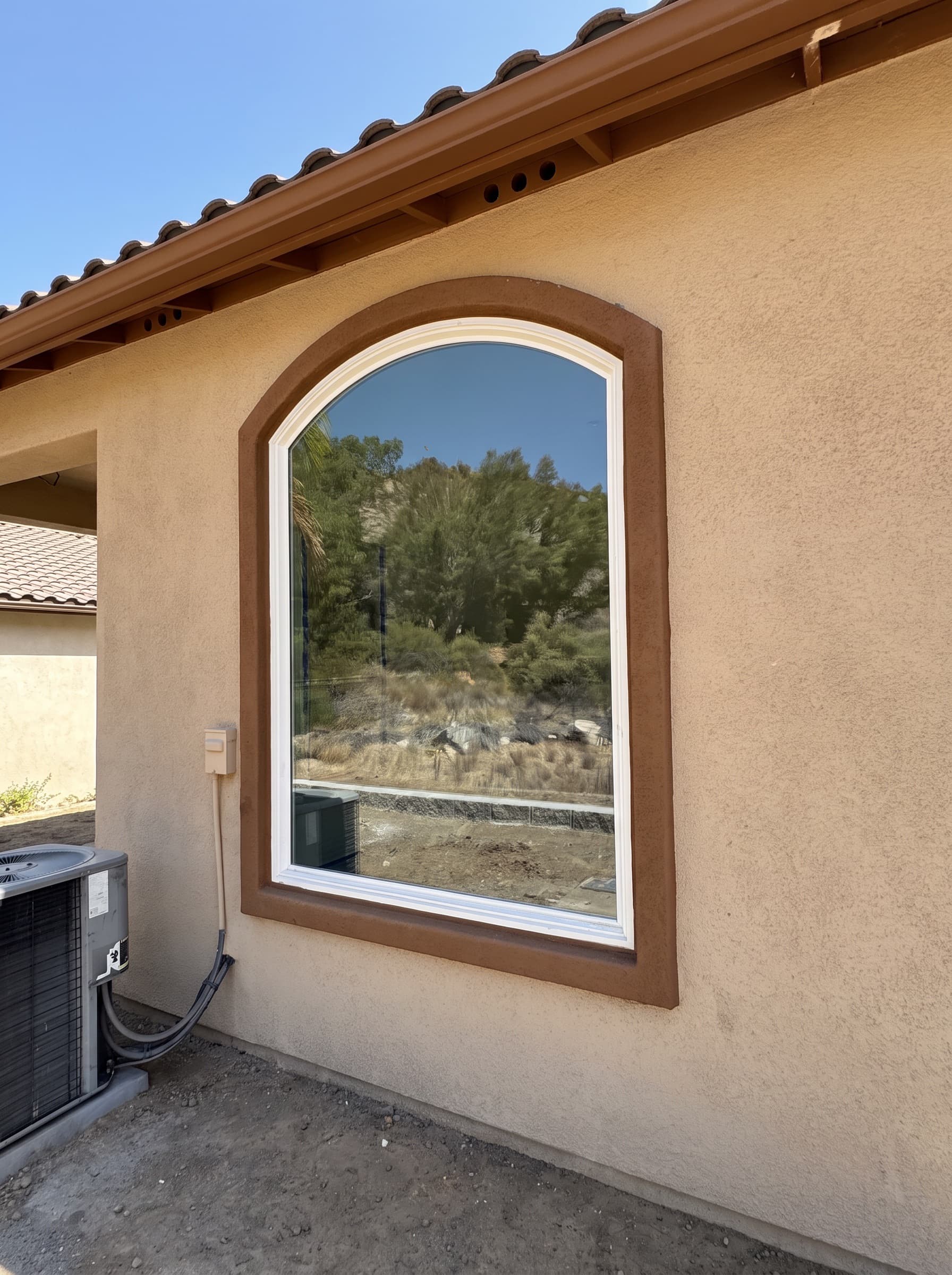 Arched window with a white frame set in a warm stucco wall